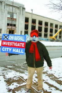 PHOTO BY CHUCK HOVEN Thursday, January 23, 2013; John Marshall High School demolition site, 3952 W. 140th Street: Wearing a gas mask, Satinder P. S. Puri stands in front of the site where cranes are demolishing the historic high school building. P.S. Puri seeks an investigation of Council President Martin Sweeney and Cleveland Mayor Frank Jackson for their complicity in orchestrating the destruction of this historic landmark. 