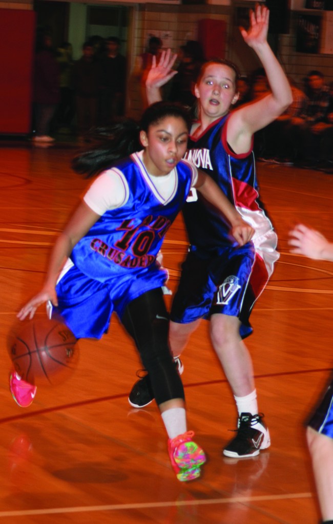 PHOTO BY CHUCK HOVEN Saturday, March 15, 2014, Girls Varsity League Ignatius Basketball Association Championship Game, St. Ignatius of Antioch School Gym, 10205 Lorain Ave: Jenine Saba of the Holy Cross Lady Crusaders drives past Villanova Lady Wildcats defender Oceannay Davis on her way to the basket. The Lady Crusaders won the championship game by a score of 37-29.