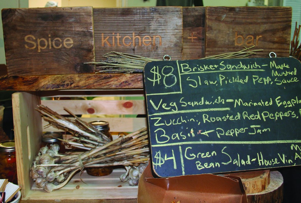 PHOTO BY CHUCK HOVEN Friday, June 13, 2014; Open House at 78th Street Studios, 1300 W. 78th Street: Spices, a local restaurant, offers a selection of items for lunch for guests touring artists’ studios during the Open House. Each Friday, some of artists at W. 78th Street Studios open their studios for the public to view. Artist Suzie Frazier designed the sign (Spice kitchen + bar) for the restaurant. Frazier has a studio near the lunch counter.