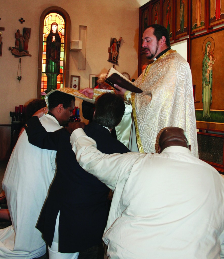 PHOTO BY CHUCK HOVEN Sunday, August 3, 2014; St. Helena Romanian Byzantine Catholic Church, 1367 W. 65th Street: Fr. Petru Stanea Antwain confirms Anthony Thomas (white robe) while Godfather Jack Craciun III and Alternate Godfather Robert Weakley kneel at his side.  