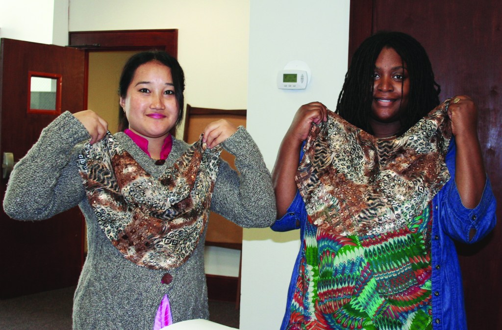 PHOTO BY CHUCK HOVEN Thursday, October 16, 2014; Esperanza Threads, 1370 W. 69th Street: (L-R) Pramila Subba and Ramona Priah hold up pieces of fabric they have cut to make into scarfs. 