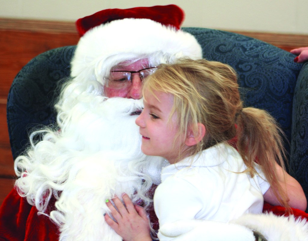 PHOTO BY CHUCK HOVEN Thursday, December 11, 2014; H. Barbara Booker Holiday Party & Musical Program, 2121 W. 67th Street: A student sits in Santa’s lap and lets him know what she would like for Christmas. Later in her classroom she will receive a gift from Santa from her Christmas wish list. Sherwin-Williams’ employees purchased the gifts for the children. H. Barbara Booker staff member Paula Kasner coordinated the event, making sure to match each student with a Sherwin-William employee.