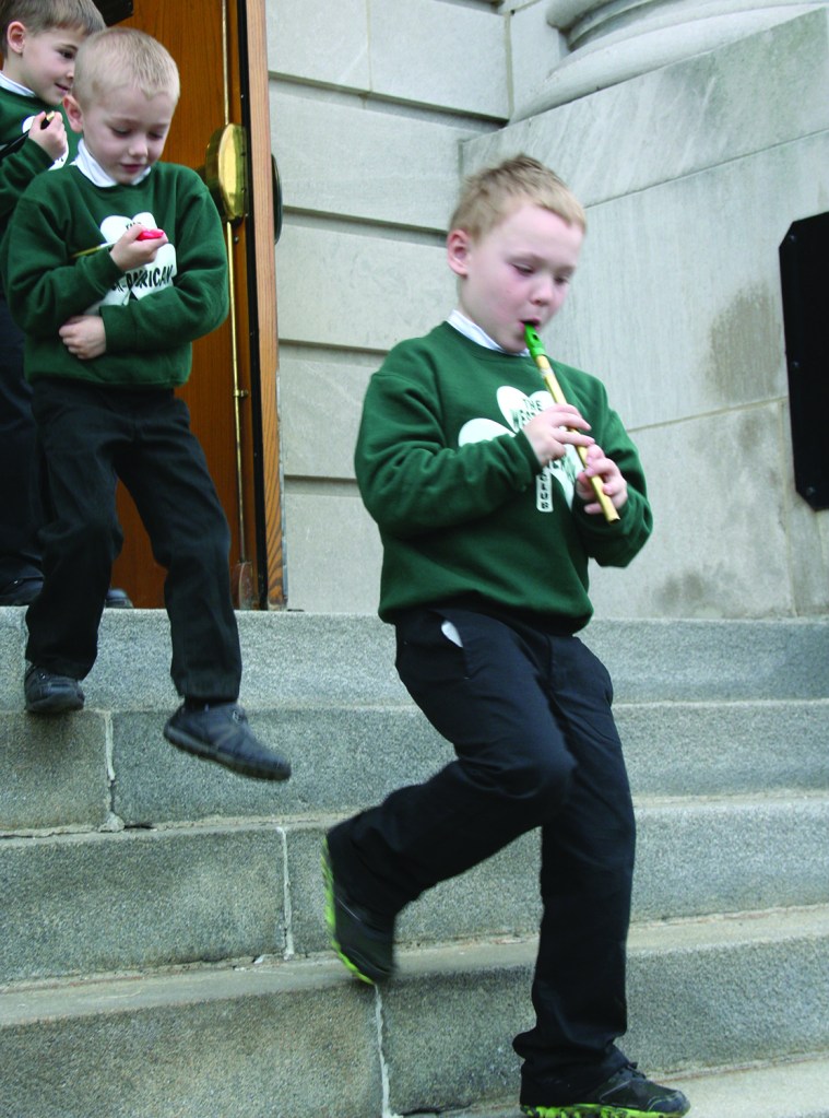 PHOTO BY DEBBIE SADLON Tuesday, March 17, 2015; St. Colman Church, 2027 W. 65th Street: A young boy plays the tin whistle as he walks down the steps of St. Colman Church after mass.