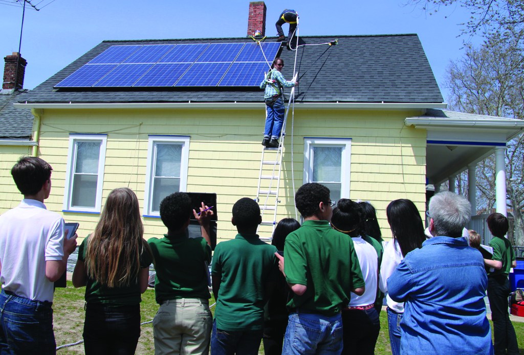 PHOTO COURTESY OF APPROPRIATELY APPLIED TECHNOLOGIES Monday, April 27, 2015; House of Champions, 2067 W. 47th Street: Urban Community School (UCS) sixth grade students from Eleanor Reagan’s Science Class watch as workers from Appropriately Applied Technologies (AAT) install solar panels. AAT worked with UCS and Refugee Response to teach students about solar energy. The project included both in class instruction and real life demonstration. 