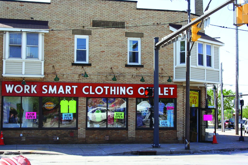 PHOTO BY DEBBIE SADLON Saturday, June 6, 2015; Work Smart Clothing Factory, 11645 Lorain Avenue: The Work Smart Clothing Store reopened in December after being closed for four months due to fire damage. Owner Nick Katsaros, age 79, says he first opened the store in 1980. He says the building originally housed a Cleveland Trust Bank and the vault is still in the building. Katsoros says the corner of W. 117th and Lorain Avenue used to be the end of the Street Car Line. As a child, he remembers his parents recalling that people would ride to the end of the line, and chose from four movie theatres to attend in the immediate area.