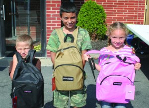 PHOTO BY DEBBIE SADLON Saturday, August 8, 2015; West 58th Street Church of God Back to School Celebration and Supply Give-A-Way, 3150 W. 58th Street: (L-R) Christopher Evcic, age 5, Cameron Evcic, age 10 and Makayla Evcic, age 6, display their new backpacks filled with school supplies.