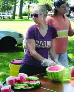 PHOTO BY DEBBIE SADLON Sunday, August 2, 2015; “We Care” Expo in Jefferson Park, 13124 Lorain Ave: We Care volunteer Bartbie Chapin passes out watermelon. Walk of Faith Community Center and Aable Rents sponsored the “We Care” Expo, which featured food, raffles and free school supplies.