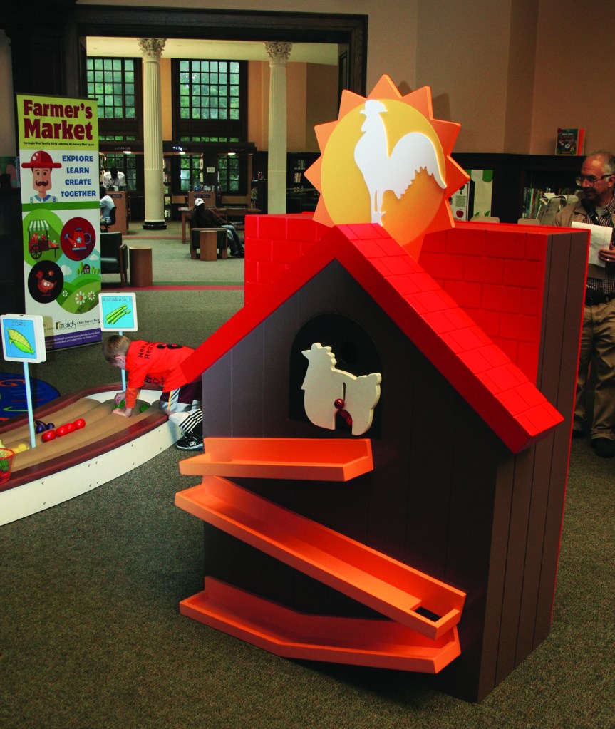 PHOTO BY DEBBIE SADLON Saturday, September 12, 2015; Carnegie West Library’s Family Learning & Literacy Play Space, 1900 Fulton Road: The chicken coop is one of the farm stations where children can gather eggs and take them to the farmers market. 
